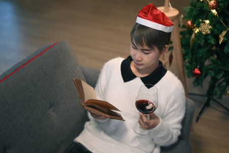 Young man wearing Christmas hat  talking to friends on video call celebrate Christmas day in distance online chat at home.の写真素材