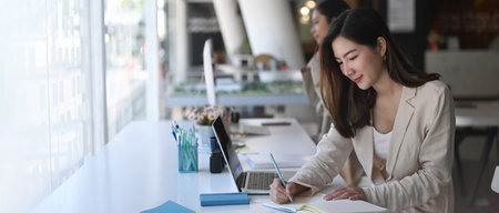 Two attractive business woman are working together in modern office.の写真素材