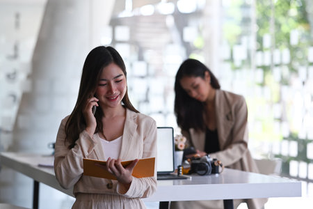Two young female freelancer colleagues working together on new project in modern office.の写真素材