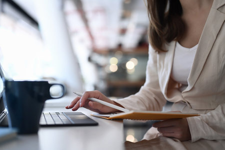 A female executive doing paperwork at workplace and using computer tablet for data analysis.の写真素材