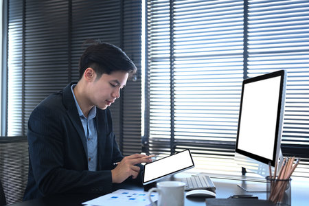 Businessman using computer tablet researching process accounting  and analysis market graph data stock information review on the table in office.の写真素材