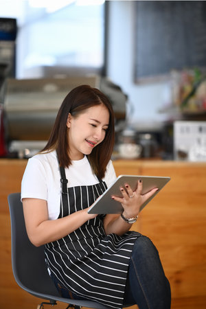 Young woman barista smelling and checking quality of coffee beans at coffee shop.