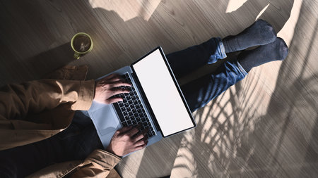 Over head shot of casual man freelancer sitting on floor and working on laptop computer with blank screen.の写真素材