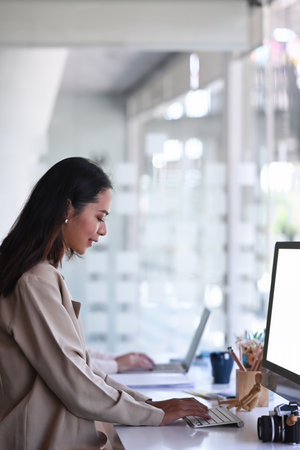 Portrait of female designer concentrate working on digital tablet while sitting at creative workspace.の写真素材