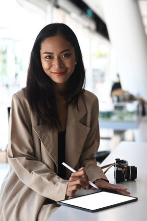 Portrait of cheerful creative designer sitting in office and working on digital tablet.の写真素材