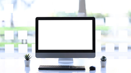 Top view of mock up tablet device with blank screen over a wooden workspace table.