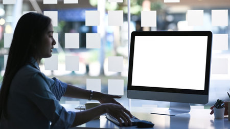 Side view of attractive Asian businesswoman working with computer in modern office.の写真素材