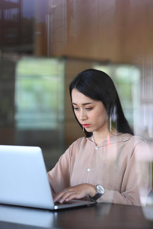Portrait of businesswoman using laptop computer working on new project idea at her workspace.の写真素材