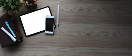 Side view of computer with blank screen and tablet on modern workstation.