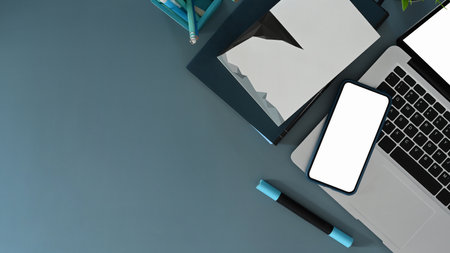 Mock up laptop computer with blank screen, office supplies and coffee cup on white office desk.の写真素材