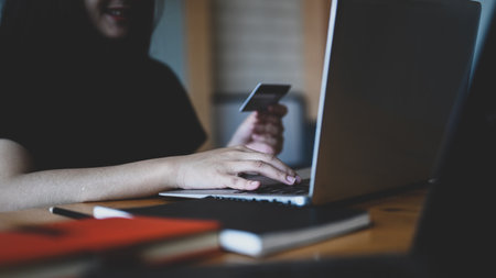 Cropped shot of young woman holding credit card and using laptop computer for online shopping or payment transaction.の写真素材