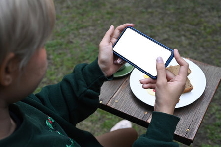 Young Asian girl using smart phone taking photo of sweet desserts for social network picture.