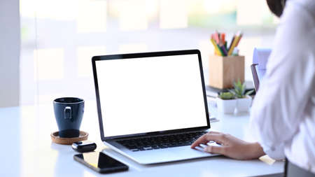 Close up view of young female employee working on laptop commuter at office desk.の写真素材