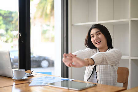 Happy businesswoman  relaxing in comfortable office and stretching during break after work done.