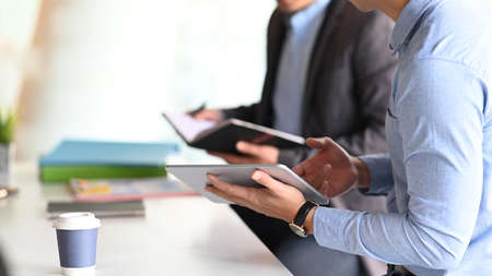 Young woman browsing websites on laptop and using mobile phone at office.の写真素材
