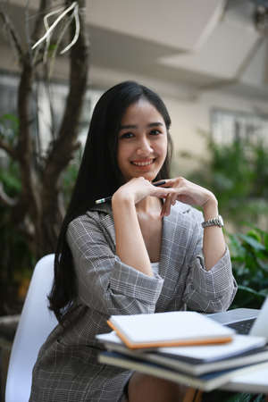 Cropped shot of businesswoman working with laptop computer and writing on empty notebook.の写真素材
