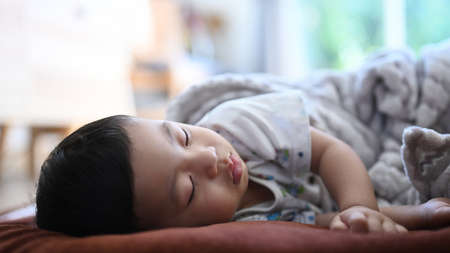 Close up view of baby boy sleeping on bed at home.の写真素材