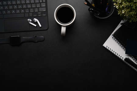Top view of creative designer workspace with smart watch, notebook, wireless keyboard, color swatches and copy space on black table.の写真素材