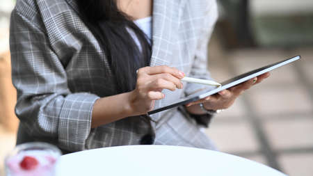 Cropped shot of young female freelancer working with digital tablet while sitting at cafe.の写真素材