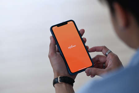 CHIANG MAI,THAILAND - FEB 08, 2021 : Man holding I Phone 11 Pro max opening Payoneer app.  Payoneer is financial company that provides online money transfer and digital payment services.のeditorial素材