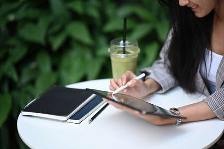 Young female freelance working with laptop computer and writing her idea on notebook.