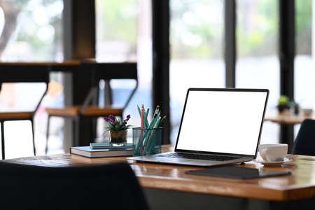 Overhead shot of contemporary workspace with laptop computer, coffee cup, notebook and copy space on black table.の写真素材