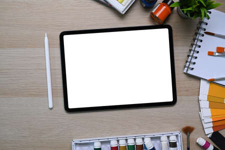 Horizontal image of dark office desk with digital tablet, stylus pen, laptop, coffee cup and notebook.の写真素材