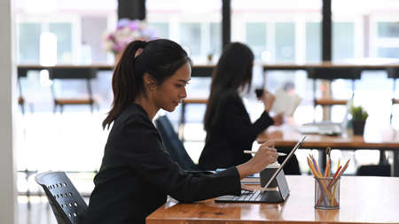 Two businesswoman colleagues sharing ideas about new corporate strategy at modern office.の写真素材