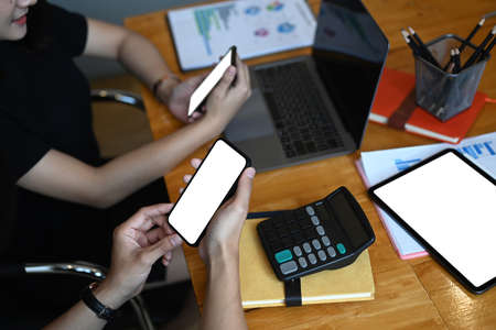 Cropped shot of male and female financial experts discussing information during accounting process and using mobile phone.の写真素材