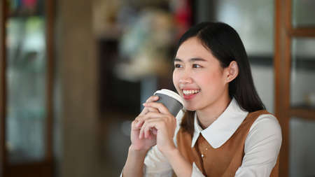 Young Asian woman body temperature checking before access to building by infrared forehead thermometer.の写真素材