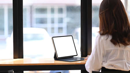 Confident businesswoman showing digital tablet while sitting in office. Blank screen for your...