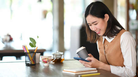 Portrait of young woman entrepreneur using digital tablet while sitting in modern coffee shop.の写真素材