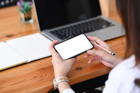 Cropped shot of businesswoman holding horizontal mobile phone watching social media at her...
