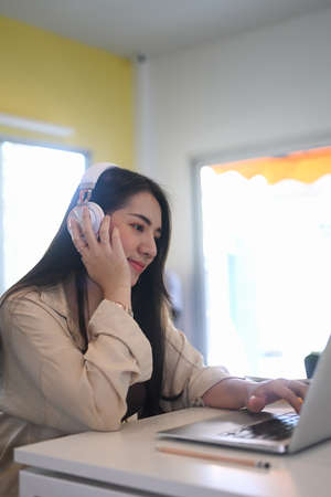 Chubby attractive young female freelancer wearing headphone working with computer laptop at her...