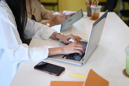 Mock up digital tablet with empty screen, notebook, coffee cup and plant on orange background.