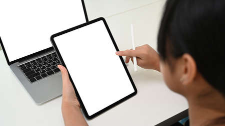 Close up view of young girl using smart phone during studying online with computer laptop.
