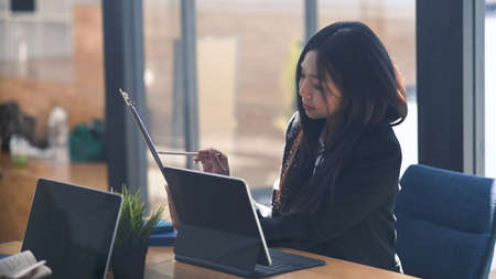 Attractive businesswoman working with computer tablet and analyzing document at modern office.の写真素材