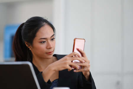 Cheerful stylish woman using stylus pen writing on computer tablet while sitting at modern office.の写真素材
