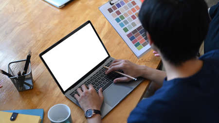 Young man sitting with crossed leg in office and using smart phone.の写真素材