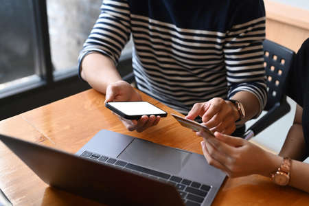 Close up view of casual female sitting in cafe and using digital tablet and stylus pen.