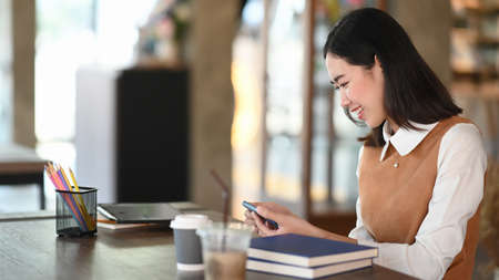 Young female holding digital tablet and thinking about her project while sitting in modern coffee shop.の写真素材