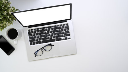 Overhead shot of mock up computer laptop, smart phone, coffee cup and copy space on white...