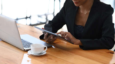Happy businesswoman sitting in front of computer laptop and using digital tablet.