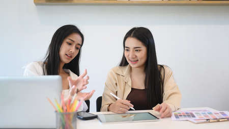 Young female explaining new idea to her colleague in creative office.