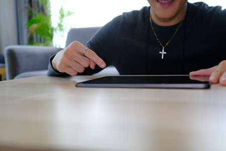 Young male university student doing some homework and using smart phone.