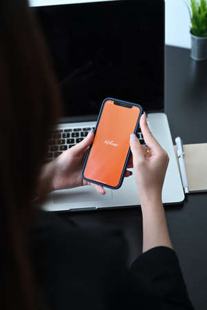 Chiangmai, Thailand -21 February 2021 : Close up view off businesswoman holding IPhone 12 with Payoneer application. Payoneer is online electronic finance payment system.のeditorial素材