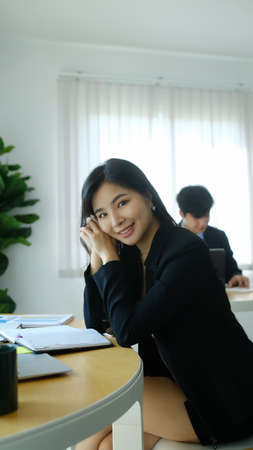 Portrait of attractive businesswoman smiling to camera while relaxing at her workplace.の写真素材