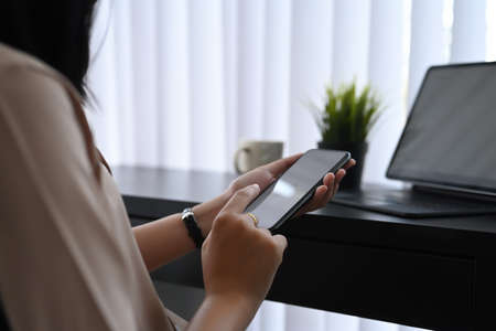 Side view of young female office worker typing on keyboard of digital tablet while sitting in...