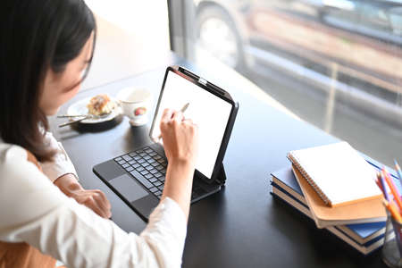 Close up view of young woman sitting in cafe and holding smart phone with white screen.の写真素材