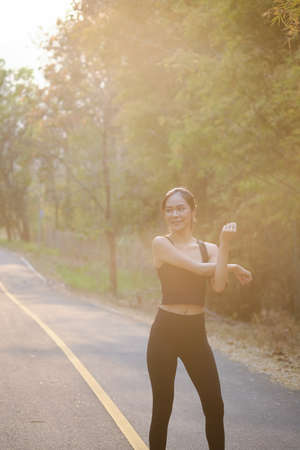 Young woman in sportswear taking a rest after jogging at the countryside road.